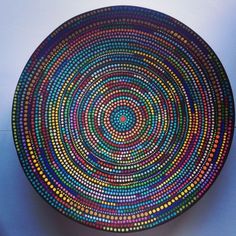 a colorful plate with dots on it sitting on top of a blue tableclothed surface