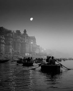 several people in rowboats on the water at night with full moon rising above them