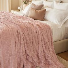 a bed covered in pink fluffy blankets and pillows