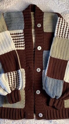 a brown and white sweater laying on top of a bed