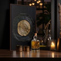 a wooden table topped with bottles and candles next to a framed art piece on top of it