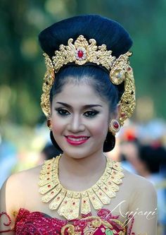 a woman wearing a red and gold dress with an elaborate headpiece on her head