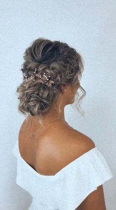 a woman with curly hair wearing a white top and gold headpiece in her hair