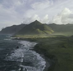 an aerial view of the ocean with mountains in the background