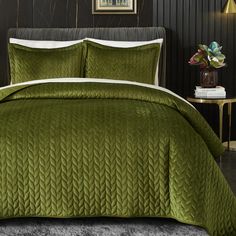 a green comforter set on a bed in a room with black walls and carpet