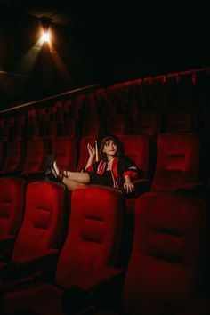 a woman is sitting in the middle of an empty theater with her legs up on the seats