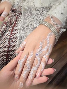 a woman's hand with white paint on it, sitting on a wooden table