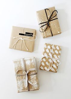 three wrapped gift boxes tied with twine on white tablecloth and two brown wrapping bags