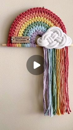 a crocheted rainbow hat hanging on a wall with a wooden stick in front of it