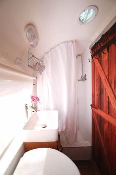 a bathroom with a toilet, sink and shower stall in the corner next to a wooden door