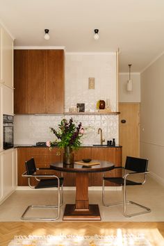 a kitchen with a table and chairs in the center, next to a microwave oven