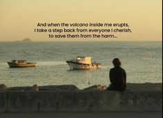 a person sitting on a wall looking out at the ocean with a boat in the distance