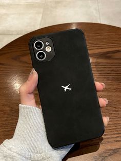 a person holding up a black phone case on a wooden table in front of a coffee table