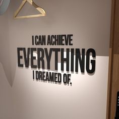 a sign that says i can achieve everything i dream of hanging on a wall next to a remote control