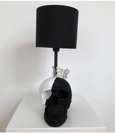 a skull lamp with a black shade on it's head sitting on a white table