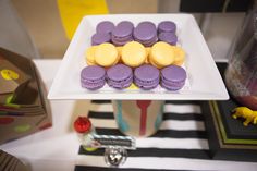 there is a plate with purple and yellow macaroons sitting on top of it