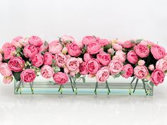 pink flowers are arranged in glass vases on a white surface