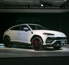 a white lamb suv is on display at an auto show in front of a black background