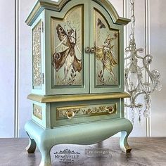 a green cabinet with butterflies painted on the front and sides, sitting on a wooden floor next to a chandelier