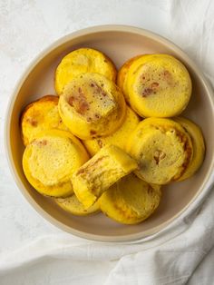 a bowl filled with yellow pastries on top of a white cloth covered tablecloth