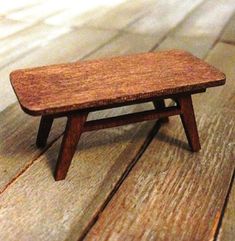 a miniature wooden bench sitting on top of a wooden floor