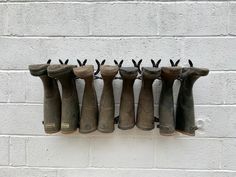 several pairs of boots hanging on a brick wall