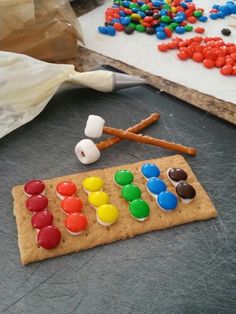 there are many different colored candies on the table next to some cookies and candy