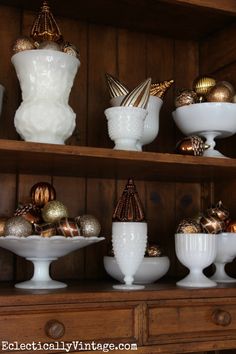 some white dishes and gold ornaments on a shelf