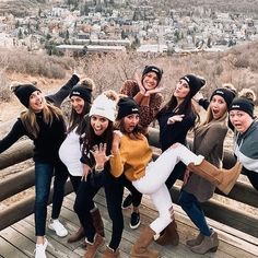 a group of young women standing on top of a wooden bridge