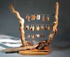 a wooden sculpture with earrings hanging from it's sides and a tree branch on the other side