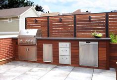 an outdoor kitchen with grill, sink and refrigerator