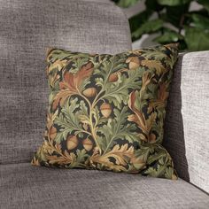 a close up of a pillow on a couch with leaves and acorns pattern