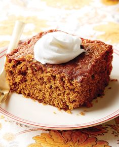 a piece of cake with whipped cream on top sits on a plate next to a fork