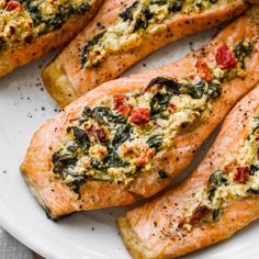 salmon fillets with spinach and cheese on a white plate, ready to be eaten