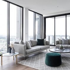 a living room filled with lots of furniture and tall glass windows next to a large window