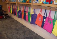 there are many bags hanging on the wall in this school room with stuffed animals and toys