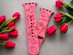 two pink watchbands sitting next to red tulips