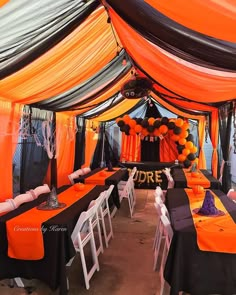 an orange and black decorated tent with white chairs