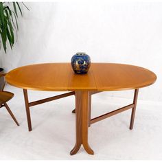 a vase sitting on top of a wooden table next to two chairs and a potted plant