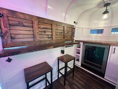 a kitchen area with stools, cabinets and an oven in the back wall that is made out of wood