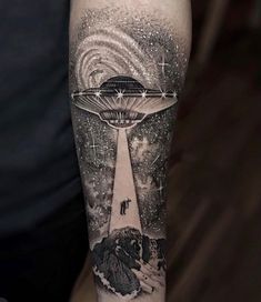 a man with a black and white tattoo on his arm that has an alien ship floating in the sky