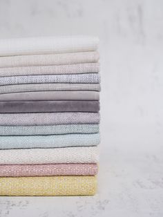 a stack of folded towels sitting on top of a white countertop next to each other