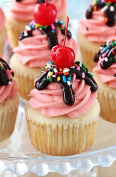 cupcakes with pink frosting and sprinkles on a glass plate