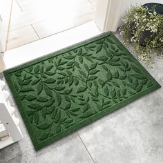 a green door mat sitting on top of a floor next to a chair and potted plant