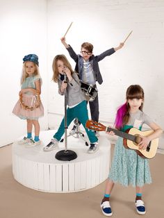 three young children are playing instruments and singing