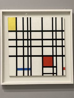 an abstract painting with black, yellow, red and blue squares in a white frame