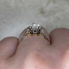 a person's hand holding a ring with two small diamonds on the middle of it