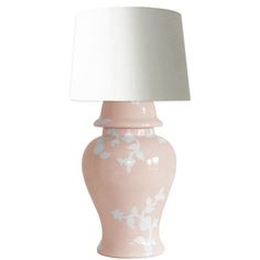 a pink and white ceramic lamp with a white shade on the top, sitting against a white background