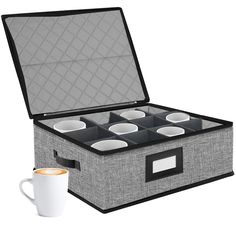 an open box with six cups in it next to a coffee cup on the table