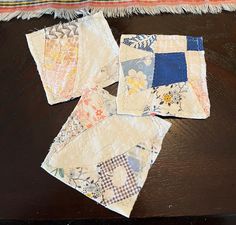 four pieces of quilt sitting on top of a wooden table next to a rug with fringes